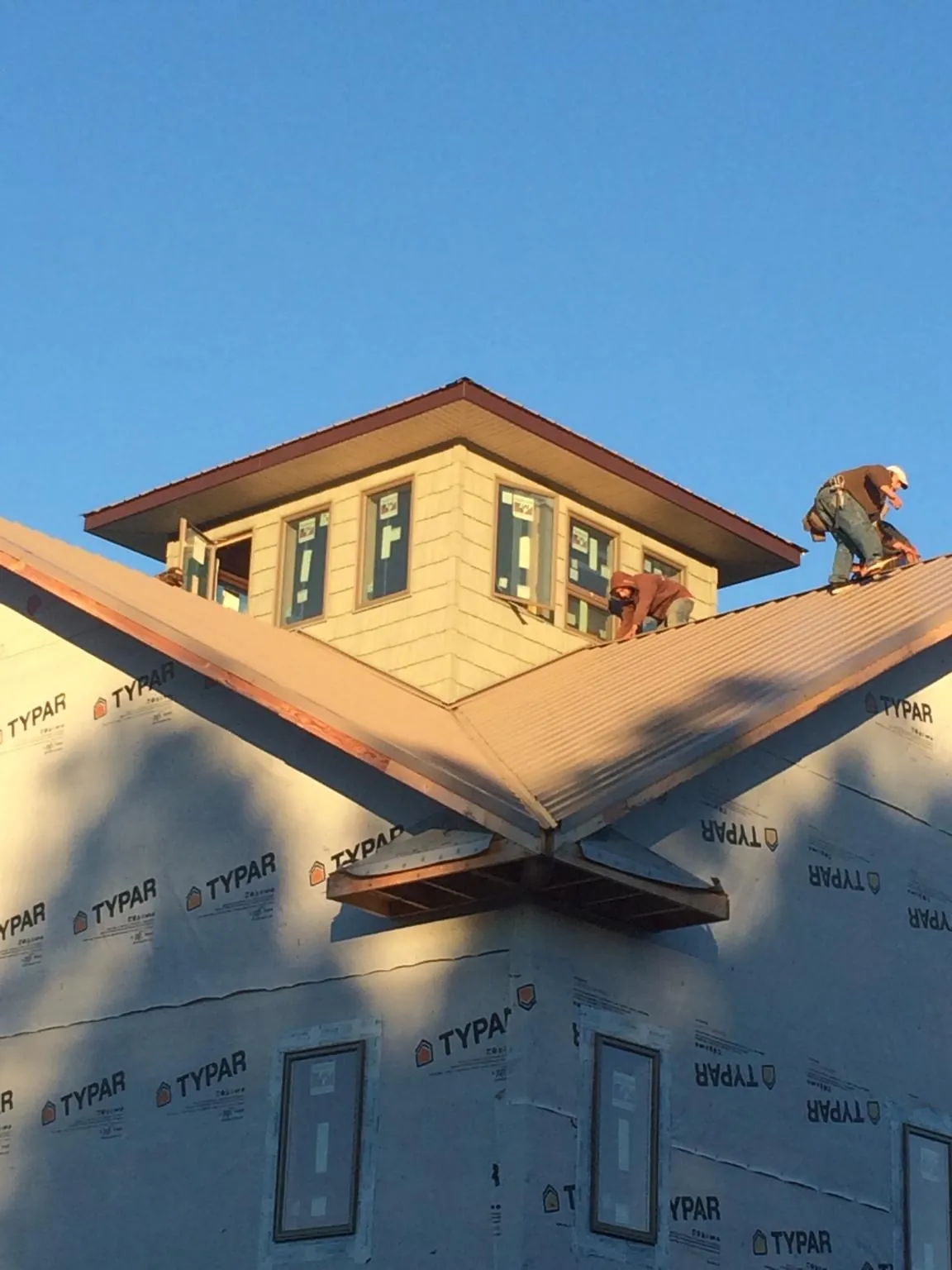 Roofers working around a rooftop cupola on a new metal roof at sunset — Roof Waterproofing in Germantown by Roofing Brothers
